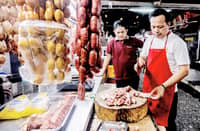 A meat vendor chops pork purchased by a customer inside a market in Quezon City on Wednesday.