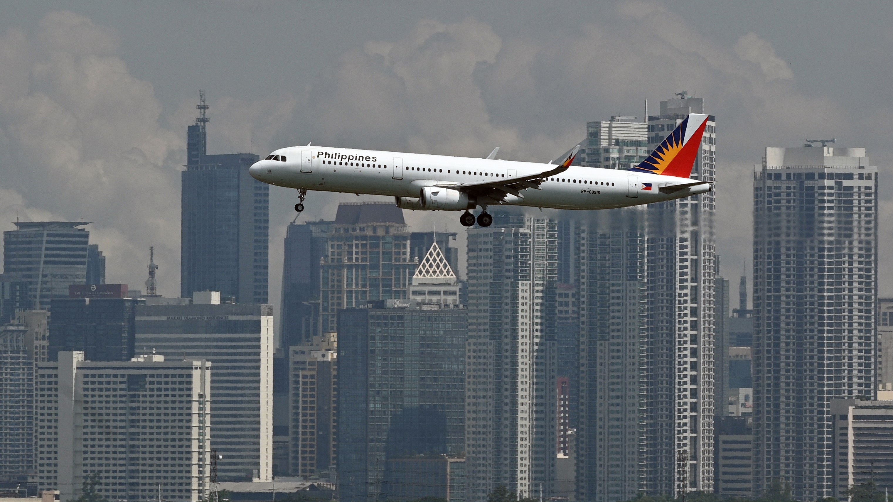 Philippine Airlines Airbus A321 passenger aircraft prepares to land at the Ninoy Aquino International Airport as the skyline of the Makati business center is seen from Taguig City.