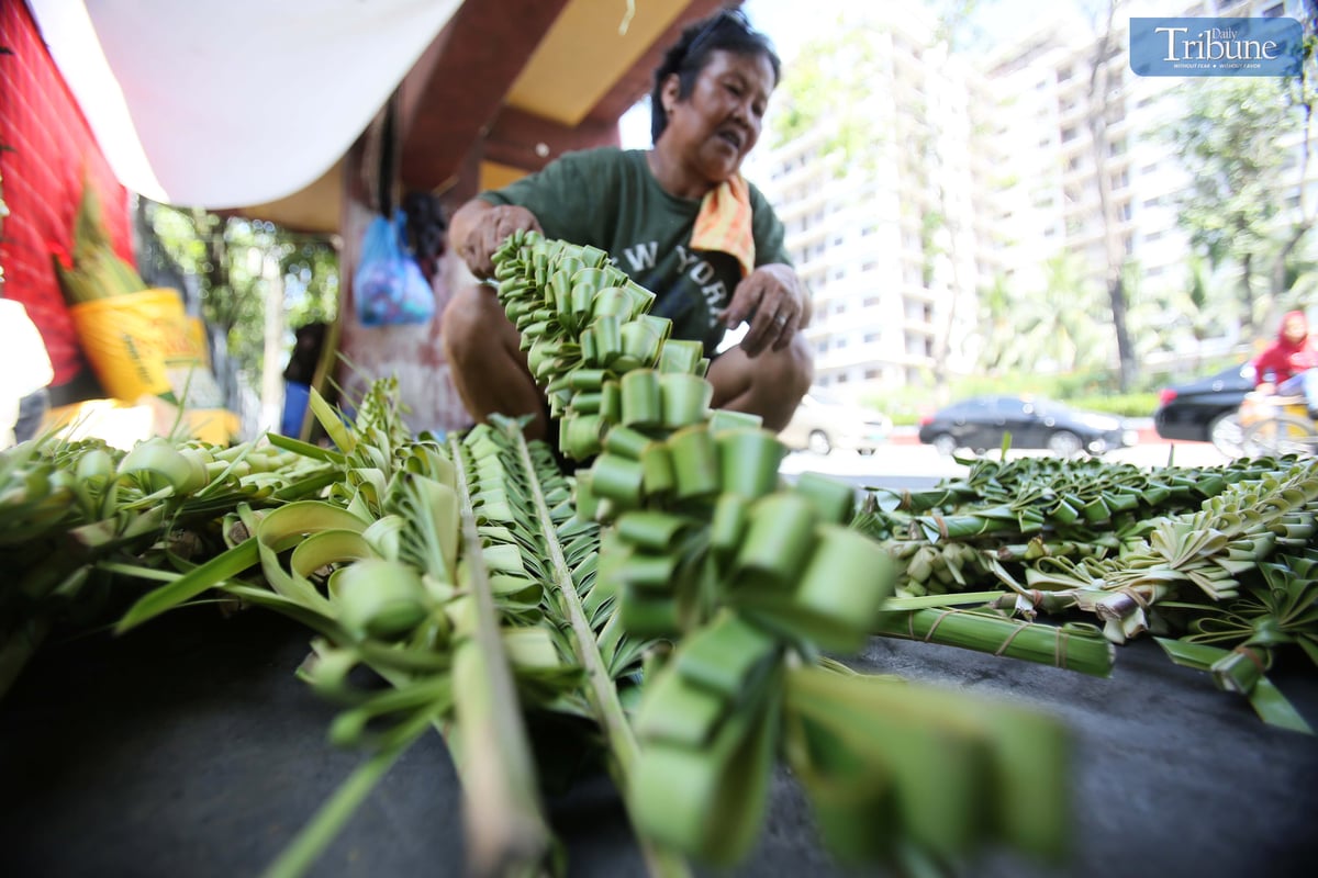 Evelyn Copper from Laguna weaves palm leaves, or palaspas, to sell for Palm Sunday in front of Santo Domingo Church — National Shrine of Our Lady of the Holy Rosary of La Naval de Manila — on Thursday, 10 April. The faithful will mark Palm Sunday on 13 April.