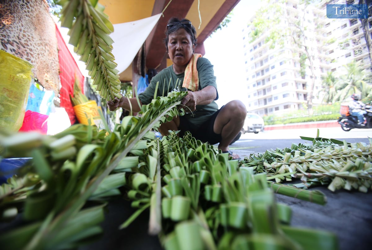 Evelyn Copper from Laguna weaves palm leaves, or palaspas, to sell for Palm Sunday in front of Santo Domingo Church — National Shrine of Our Lady of the Holy Rosary of La Naval de Manila — on Thursday, 10 April. The faithful will mark Palm Sunday on 13 April.