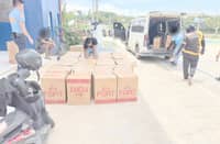AUTHORITIES examine the 54 boxes and one sack of smuggled cigarettes worth P944,000 loaded in a van after it was intercepted at a checkpoint in Barangay Sicsican, Puerto Princesa City on Tuesday.