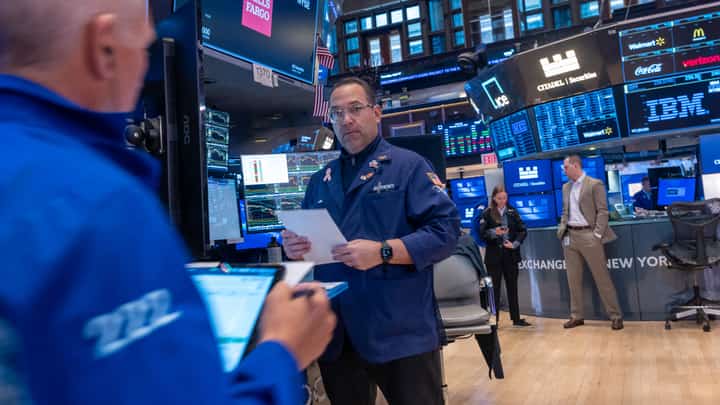 Traders work on the floor of the New York Stock Exchange (NYSE) surrounded by monitors displaying financial data and stock tickers, as concerns about a potential U.S. recession mount in April 2025.