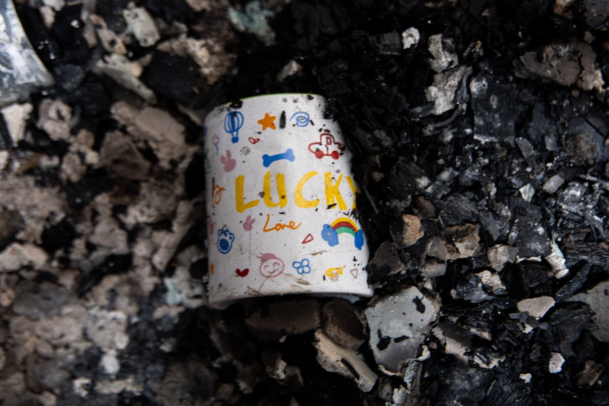 A mug that has letter markings "Lucky" inside a destroyed house.