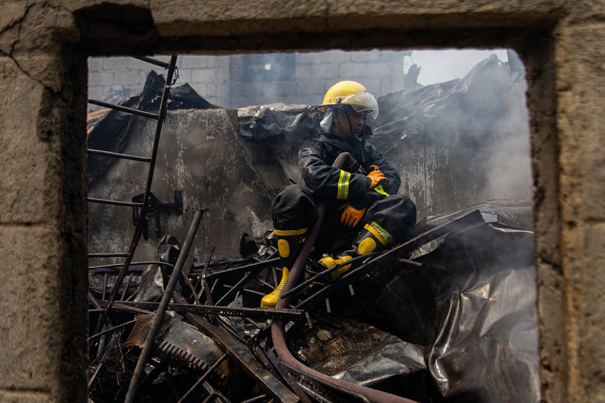 A firefighter sits on top of debris caused by the massive fire, taking a rest after putting out the remaining flames.
