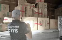 A personnel of the Bureau of Customs-Customs Intelligence and Investigation Service inspects smuggled cigarettes worth P83.7 million seized from a warehouse in Bocaue, Bulacan on Thursday.