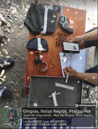 Police officers document seized items including a .38 caliber revolver, ammunition, and suspected drug-related materials on a table during a search warrant operation in Barangay Medina, Dingras, Ilocos Norte, on 23 April 2025. A map and timestamp from a GPS camera are visible in the image.