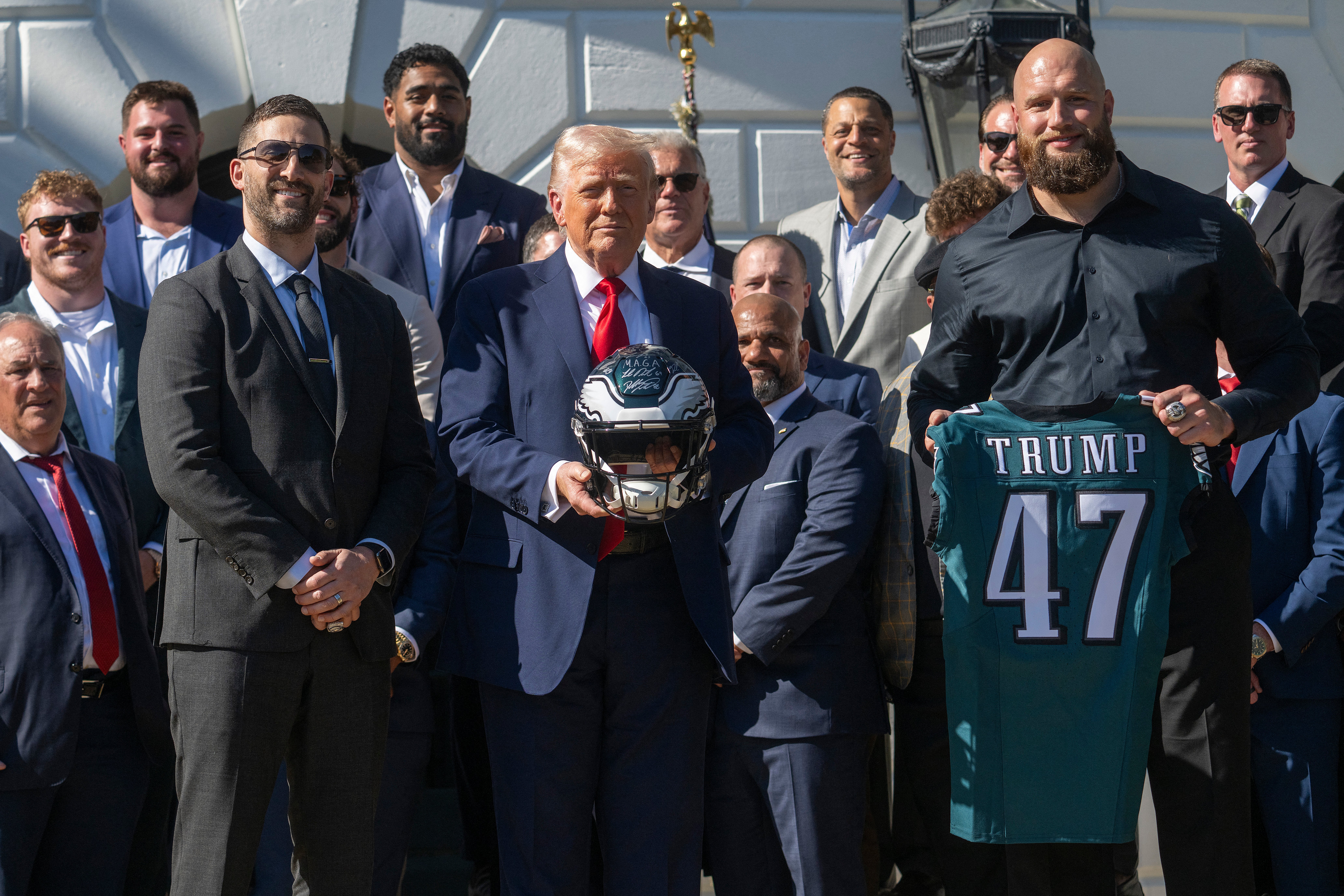 US President Donald Trump holds up a helmet, flanked by Philadelphia Eagles' tackle #65 Lane Johnson (R) and Philadelphia Eagles head coach Nick Sirianni (L), as he hosts an event celebrating the Philadelphia Eagles, 2025 Super Bowl champions, at the White House on April 28, 2025, in Washington, DC. The Eagles defeated the defending champion Kansas City Chiefs 40-22 in Super Bowl LIX, held in New Orleans, Louisiana on February 9, 2025.