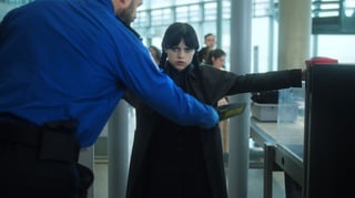 Wednesday Addams is frisked by security at an airport in a scene from season 2 of 'Wednesday.'