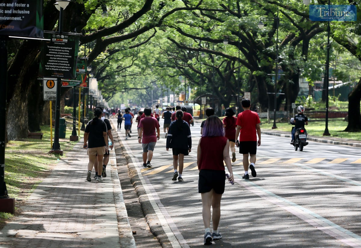 Joggers enjoy the morning sun around the academic oval at the University of the Philippines Diliman in Quezon City, Wednesday, 30 April 2025.