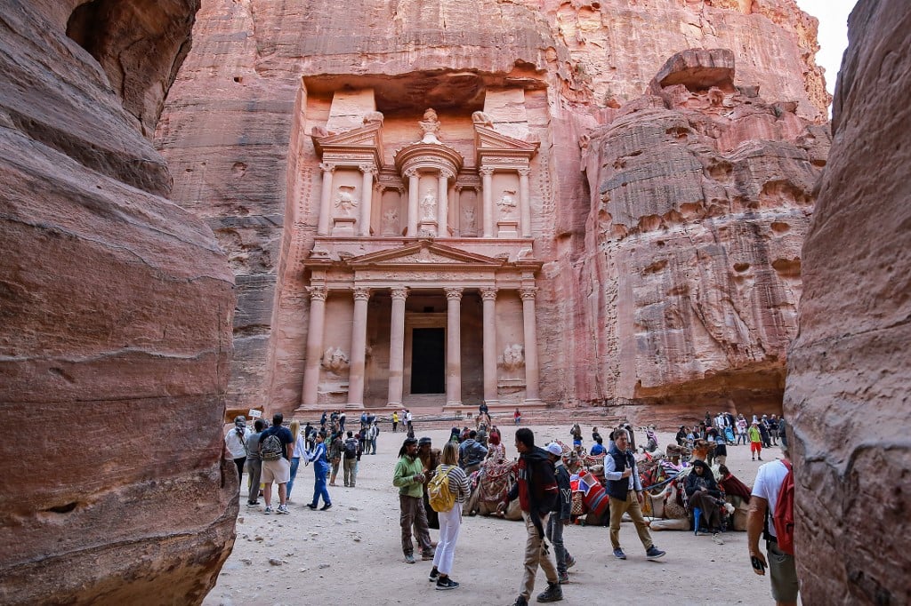 Visitors tour near the Treasury at the ruins of the ancient Nabatean city of Petra in southern Jordan on December 12, 2022. After years in which the Covid pandemic turned the storied "Rose City" into a ghost town, Jordan tourism authorities confirm that Petra, famous for its stunning temples hewn out of the rose-pink cliff faces, is back in business and drew 900,000 visitors last year, close to the previous record of one million set in 2019.