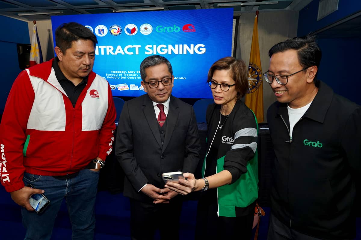 Grab Philippines chief corporate affairs officer Booey Bonifacio demonstrates to Comelec Chairman George Erwin M. Garcia how Grab users can access election reminders as part of the platform’s #RideToVote campaign.