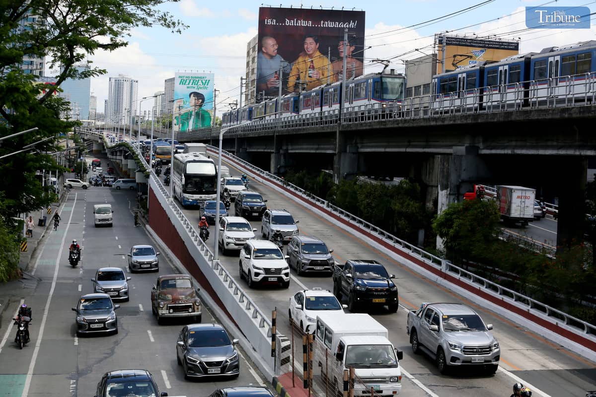 Moderate traffic builds up along EDSA near the provincial bus terminals in Cubao, Quezon City on 10 May 2025, as travelers head out two days before the national elections. MRT-3 trains and billboards loom above the roadway.