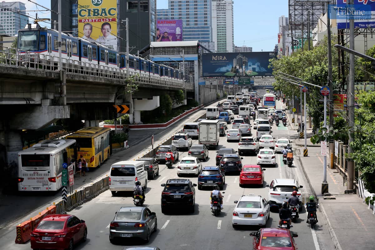 Moderate traffic builds up along EDSA near the provincial bus terminals in Cubao, Quezon City on 10 May 2025, as travelers head out two days before the national elections. MRT-3 trains and billboards loom above the roadway.
