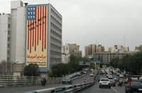 People drive past an anti-U.S. mural with the slogan "Down with the USA" and skulls replacing the stars on the flag, in Tehran on May 5, 2025.