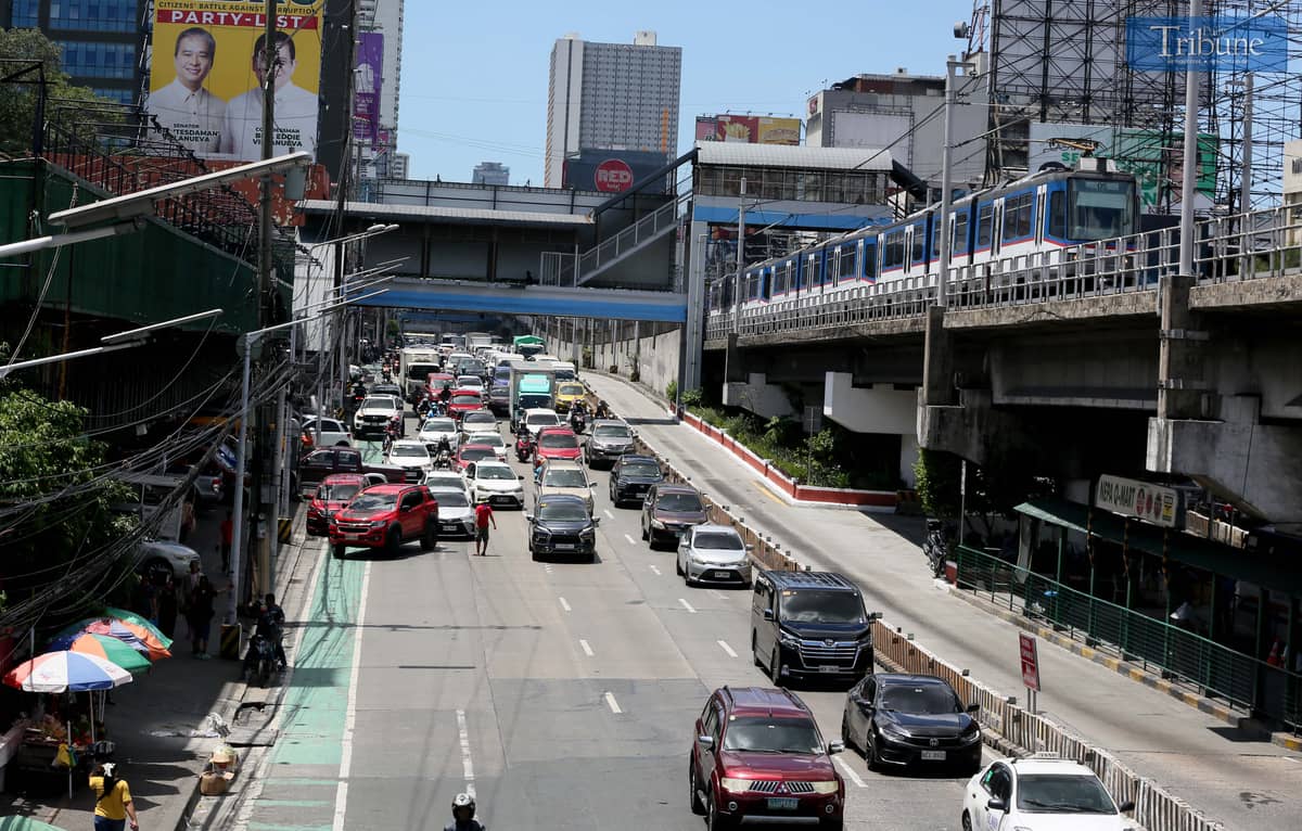 Moderate traffic builds up along EDSA near the provincial bus terminals in Cubao, Quezon City on 10 May 2025, as travelers head out two days before the national elections. MRT-3 trains and billboards loom above the roadway.