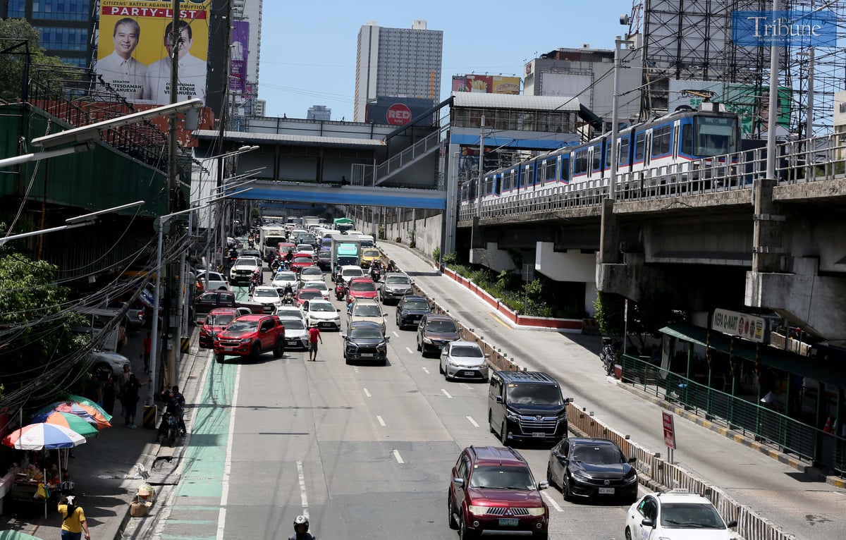 Moderate traffic builds up along EDSA near the provincial bus terminals in Cubao, Quezon City on 10 May 2025, as travelers head out two days before the national elections. MRT-3 trains and billboards loom above the roadway.