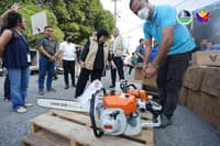 DENR Secretary Maria Antonia Yulo-Loyzaga (center) inspects seized chainsaws at a warehouse in Valenzuela City.