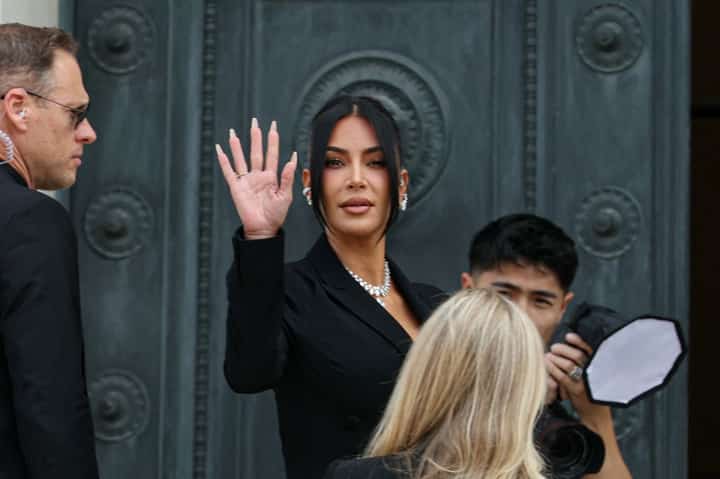 US celebrity Kim Kardashian (C) waves as she arrives at the Assize Court for the trial during which she will testify over the 2016 robbery that saw her relieved of millions of dollars' worth of jewellery at gunpoint in Paris, on May 13, 2025. The trial of this sensational nine million euro jewellery robbery opened in Paris on April 28, 2025.
