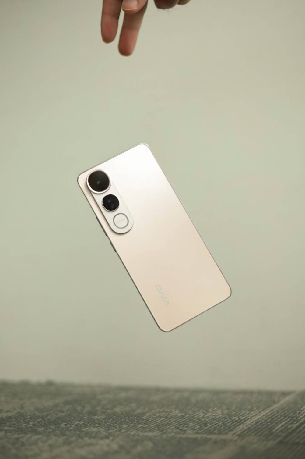 A vivo V50 Lite smartphone mid-air during a drop, showcasing its sleek design and durability features against a plain background.
