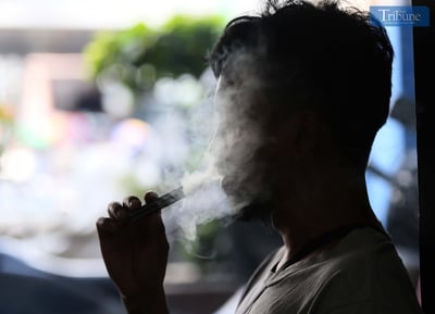 A silhouetted person exhales a large cloud of vapor while using an e-cigarette, highlighting the growing issue of youth vaping in the Philippines.