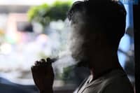 A silhouetted person exhales a large cloud of vapor while using an e-cigarette, highlighting the growing issue of youth vaping in the Philippines.