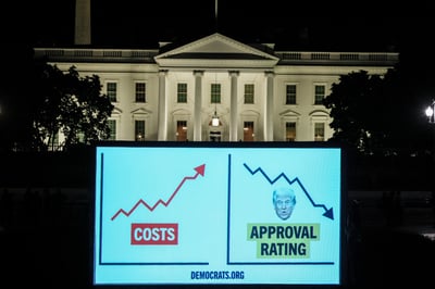 A digital projection in front of the White House displays consumer costs alongside a graphic of declining approval ratings for President Donald Trump.