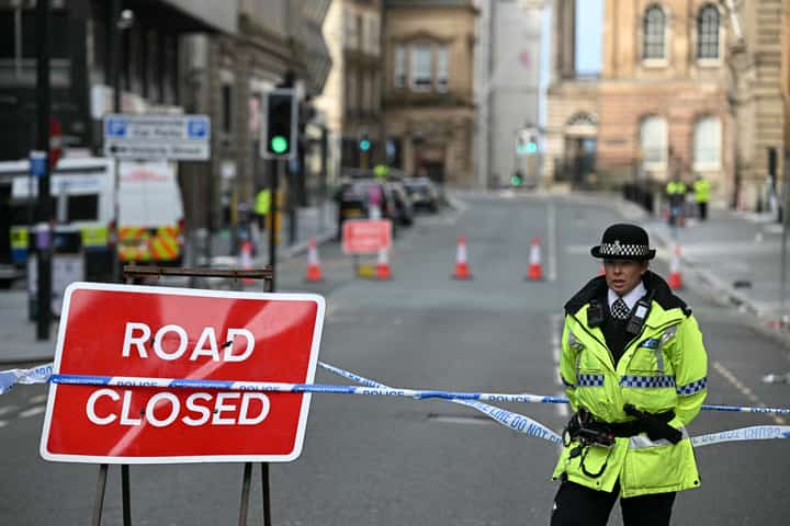 Police officers stand at a cordon in Liverpool on 27 May 2025, after a car ploughed into crowds during the Premier League title parade the previous day, injuring 27 people; police said the incident is not being treated as terrorism and a 53-year-old British man has been arrested.