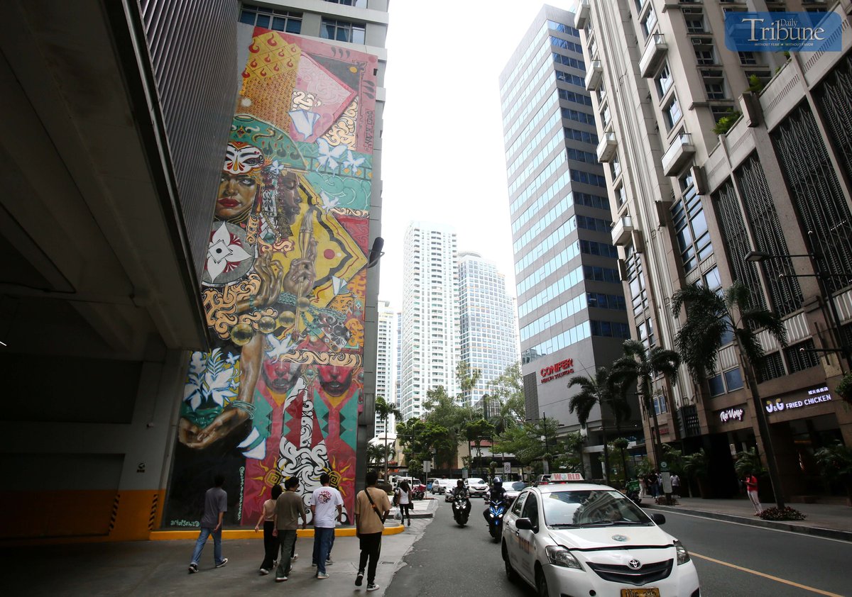 (MAY 28, 2025) On Wednesday May 28 2025, people pass by the giant mural “Mac & Qis” by Filipino-Canadian artist Sowl at a building in Eastwood City in Quezon City. Sowl said in an interview that the mural is inspired by Philippine indigenous textiles and baybayin which aims to heal and revive weary souls to whoever sees his art. Photo/Analy Labor
