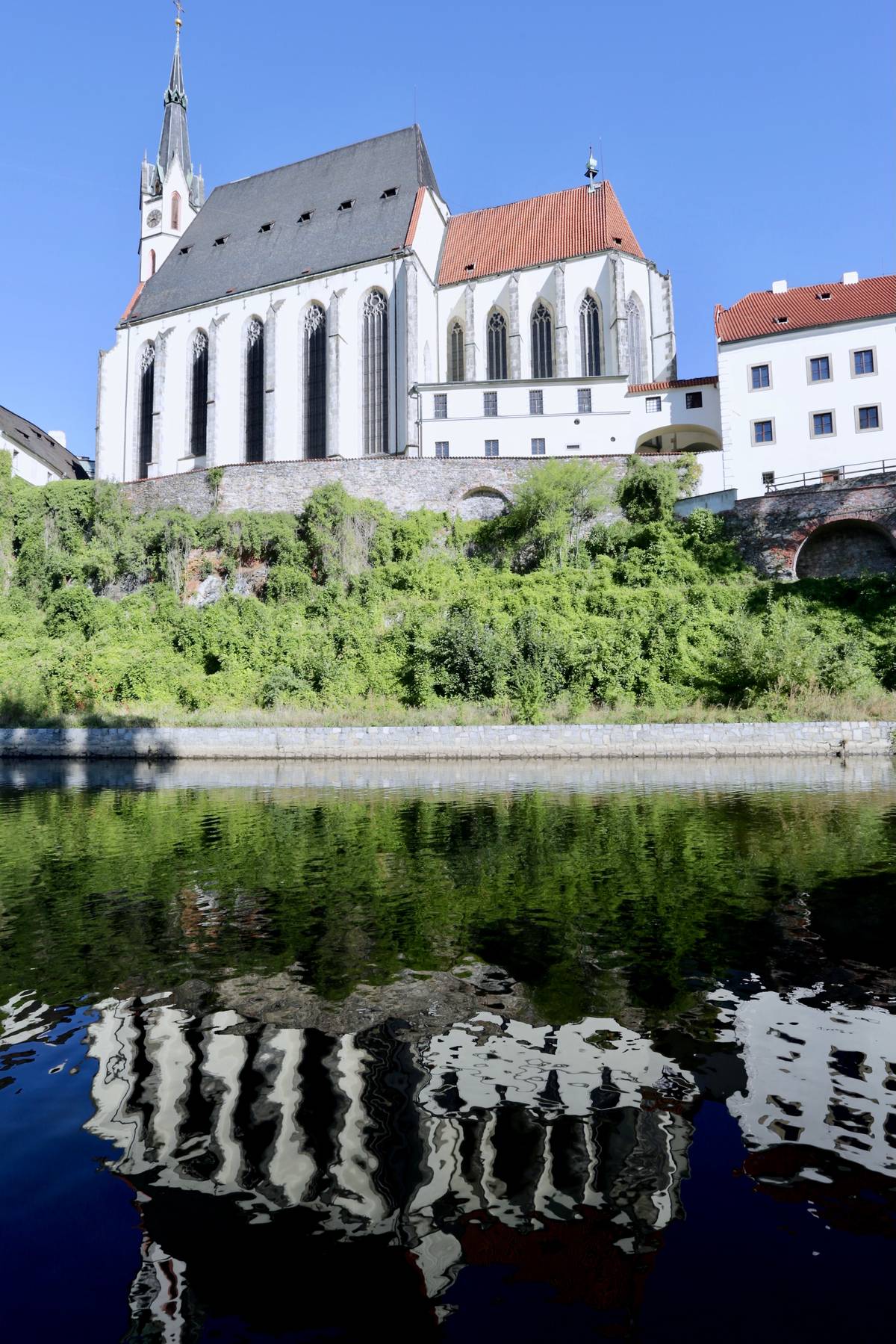 The Gothic Saint Vitus Church reflected on the river.