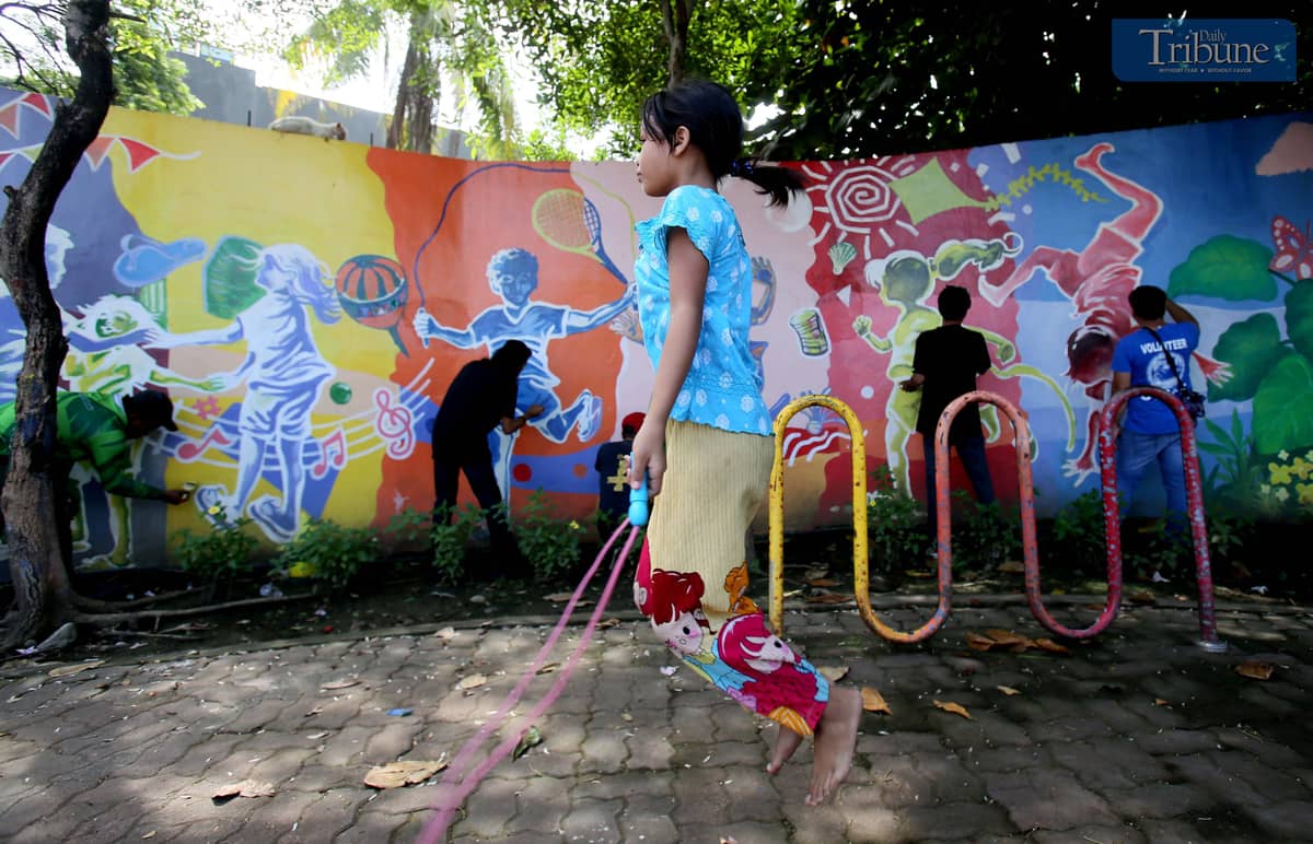 Children play nearby as a visual artist adds the finishing touches to a colorful mural at Sambag in Jaro District, Iloilo City. The artwork transforms the wall into a playful, vibrant space for the community.