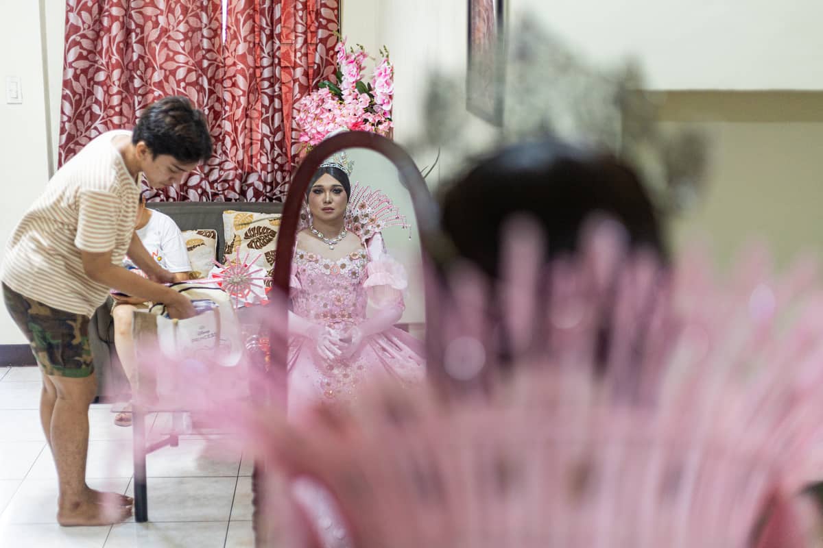 Andrei Cruz looks at himself in the mirror after wearing his gown for the Sagayla procession in Sampaloc, Manila, on Sunday, June 1, 2025.