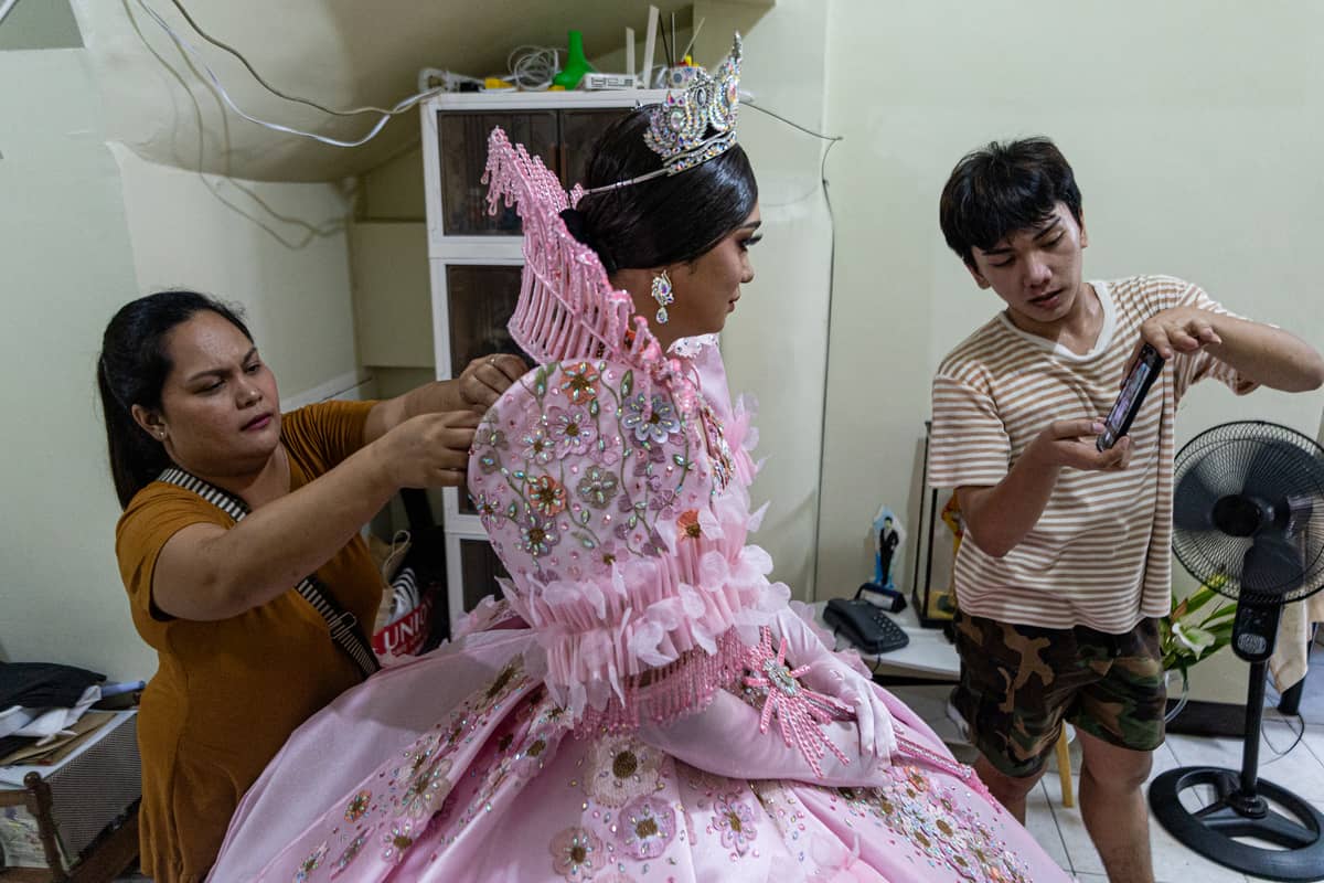 Ace Lawrence turns the front camera toward his brother, Andrei Cruz, as they help him add the finishing touches to the gown.