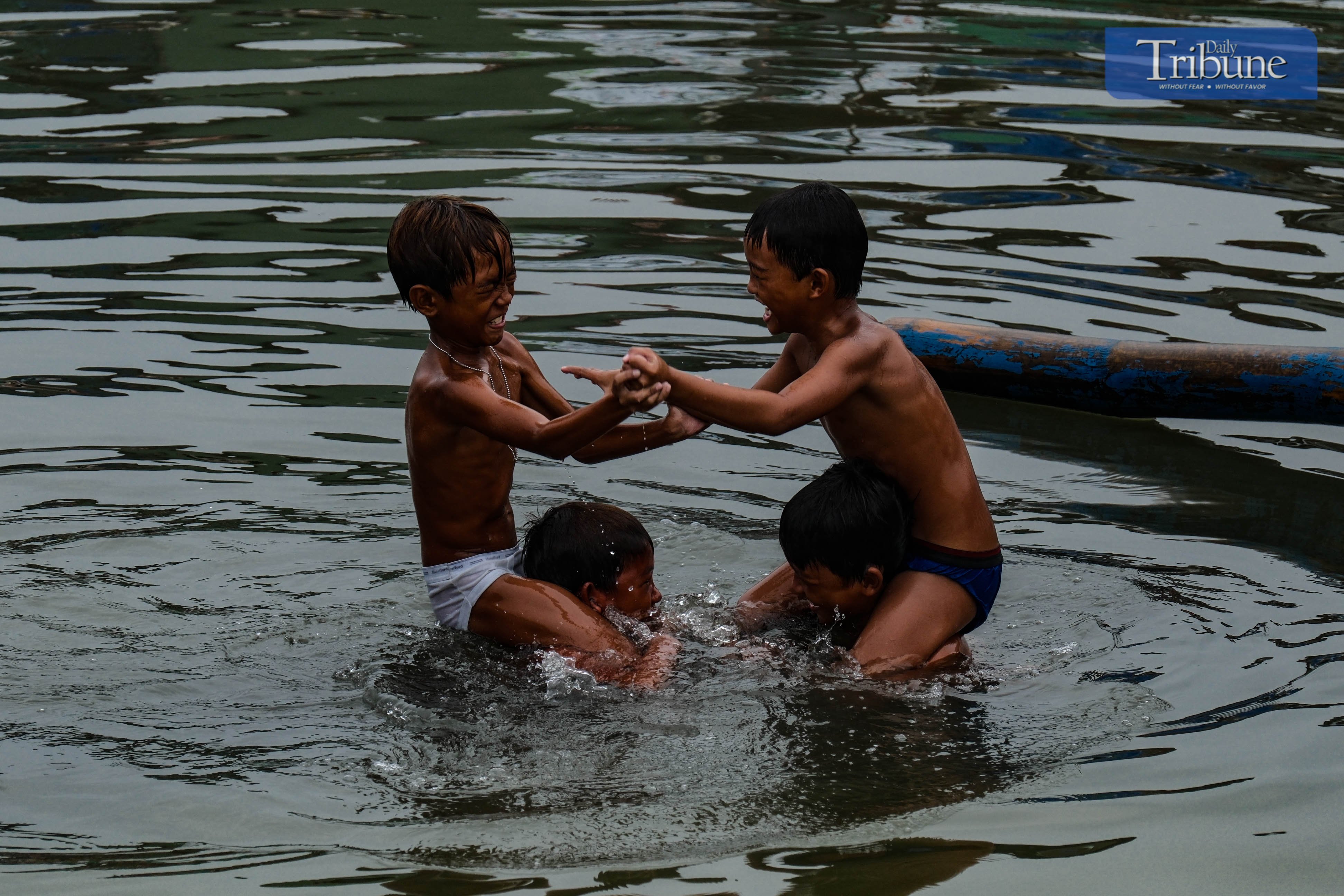 Boys cool off with a splash as they play in the waters of Navotas on Satuday, 7 June.