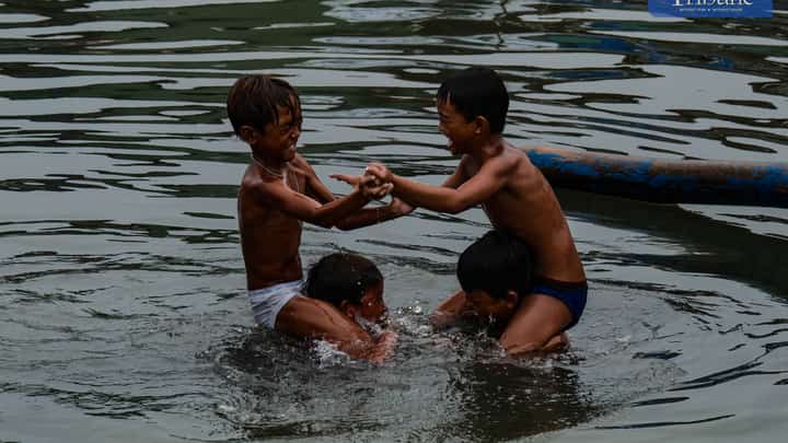 Boys cool off with a splash as they play in the waters of Navotas on Satuday, 7 June.