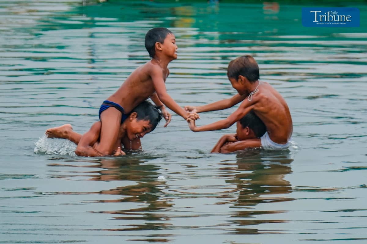 Boys cool off with a splash as they play in the waters of Navotas on Satuday, 7 June.