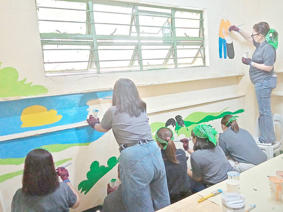 ABOITIZ Foundation president Ginggay Hontiveros-Malvar (right) and team paint a mural promoting environmental awareness at the stairwell of the TSES.