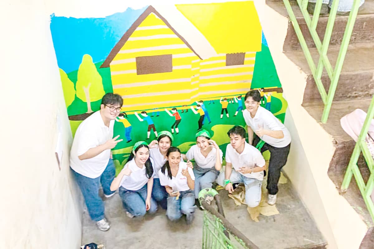 VOLUNTEERS from the Aboitiz Foundation Future Leaders Scholarship Program show the mural depicting the bayanihan tradition that they painted on a wall of the TSES as part of their Brigada Eskwela ’25 activity at the school in Quezon City.