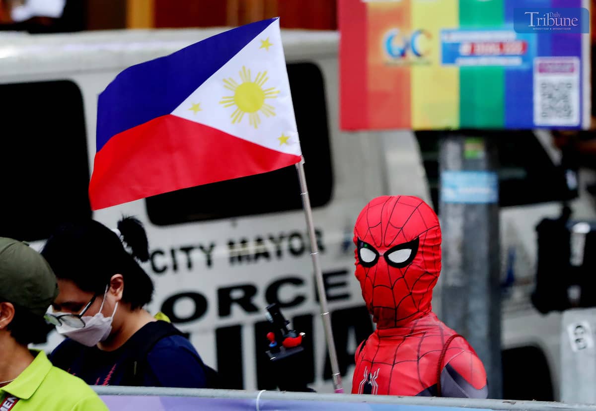 A man dressed as Spider-Man holds a Philippine flag along Tomas Morato Avenue in Quezon City on Tuesday, days ahead of the Independence Day celebration.