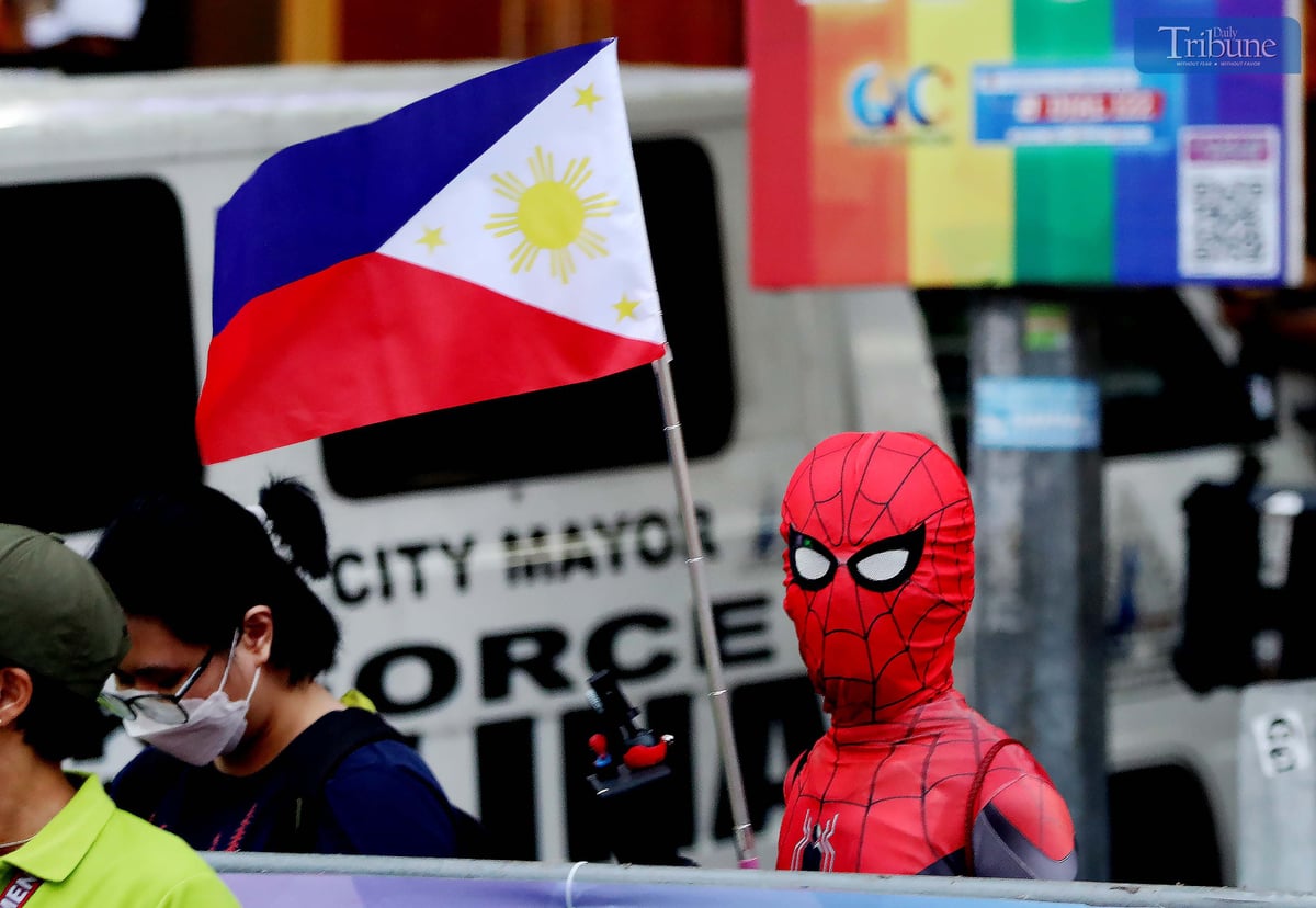 A man dressed as Spider-Man holds a Philippine flag along Tomas Morato Avenue in Quezon City on Tuesday, days ahead of the Independence Day celebration.