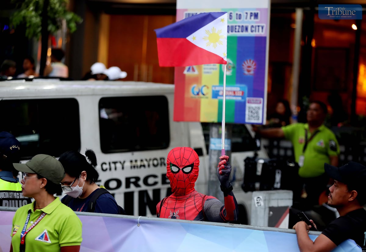 A man dressed as Spider-Man holds a Philippine flag along Tomas Morato Avenue in Quezon City on Tuesday, days ahead of the Independence Day celebration.