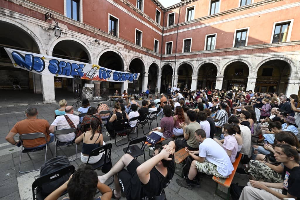 People gather to protest against the wedding of Amazon Founder and CEO Jeff Bezos and journalist Lauren Sanchez in Venice, on June 13, 2025. Poster campaigns and stickers have spread throughout the city, including one with images of Bezos reading "No space for Bezos" as some local residents protest claiming the city is transformed into a playground for billionaires.