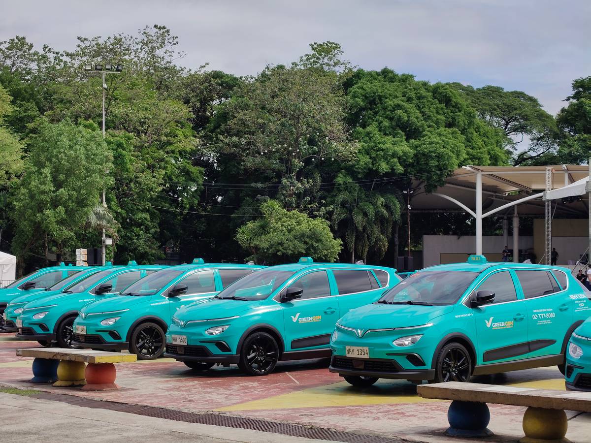 A full row of Green GSM electric taxis lines up at Quezon Memorial Circle.