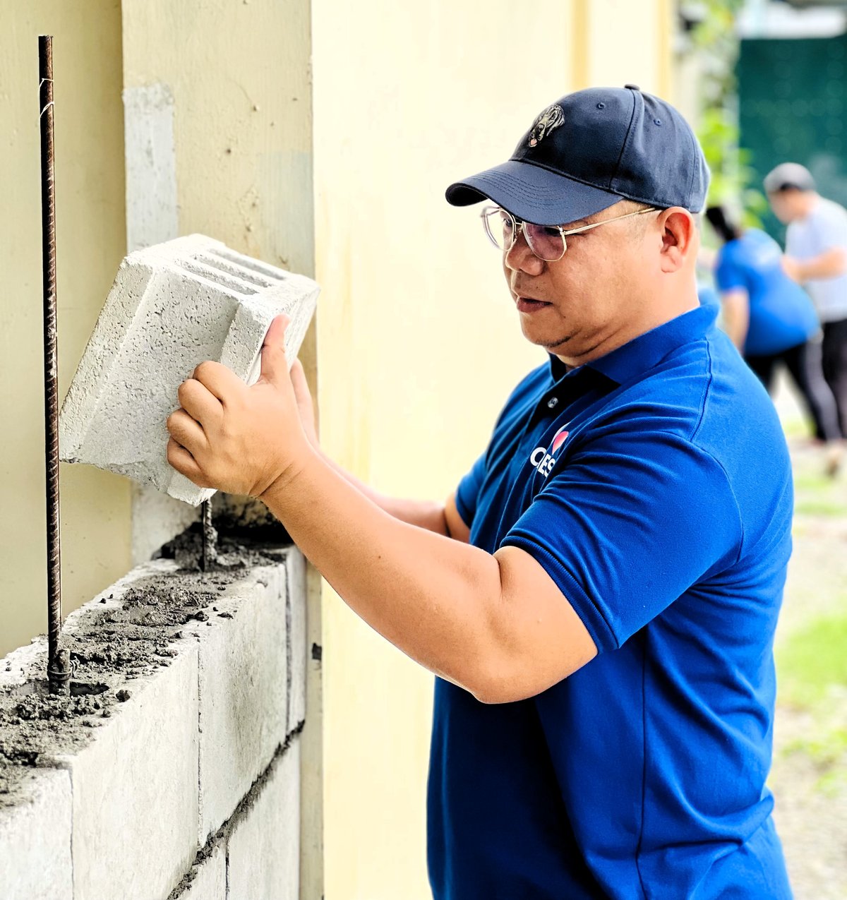 DEMONSTRATING hands-on commitment, an employee volunteer from SM City Baliwag carefully stacks hollow blocks — contributing to stronger school infrastructure.
