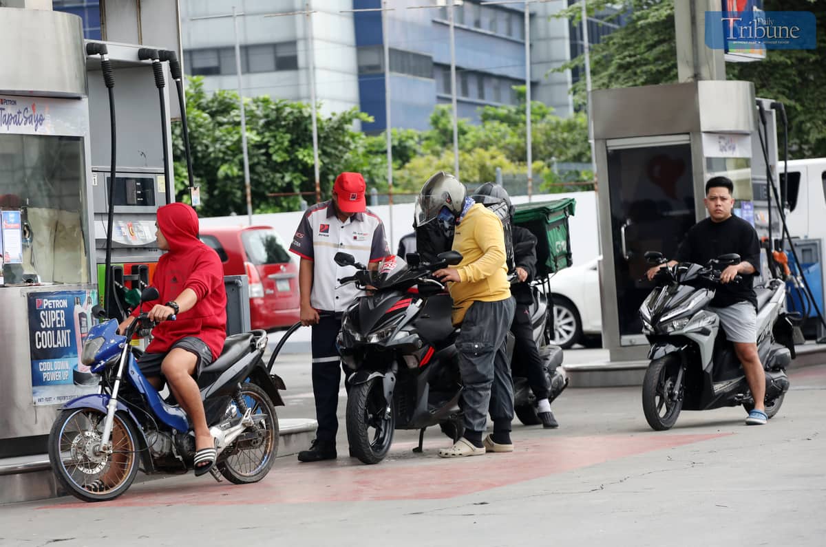 Gas station personnel assist motorists at a pump in Brgy. UP Central along Commonwealth Avenue, Quezon City, on Monday. The Department of Energy warned that diesel prices could surge by up to ₱5 per liter starting Tuesday, driven by rising global oil prices. Following a meeting with the DOE, oil companies agreed to implement the hike in staggered installments to ease the burden on consumers.