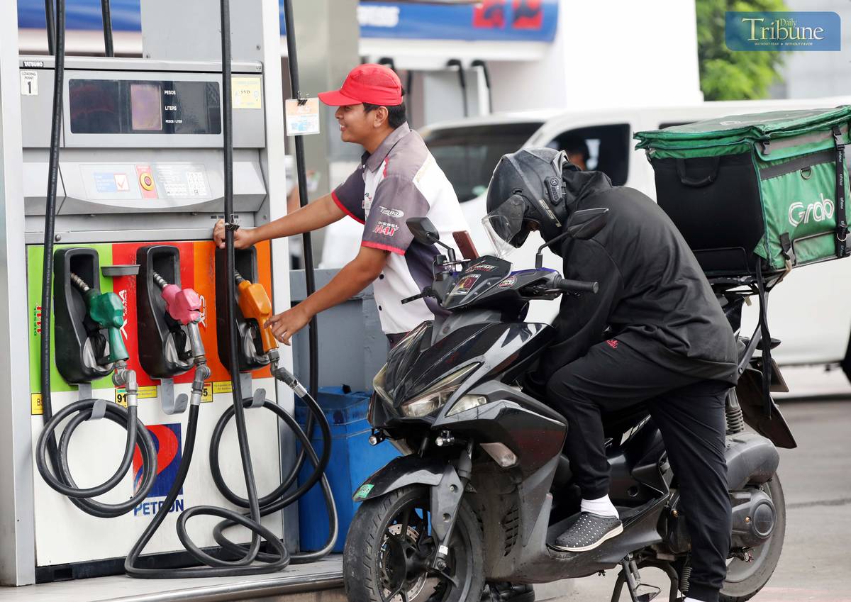 Gas station personnel assist motorists at a pump in Brgy. UP Central along Commonwealth Avenue, Quezon City, on Monday. The Department of Energy warned that diesel prices could surge by up to ₱5 per liter starting Tuesday, driven by rising global oil prices. Following a meeting with the DOE, oil companies agreed to implement the hike in staggered installments to ease the burden on consumers.
