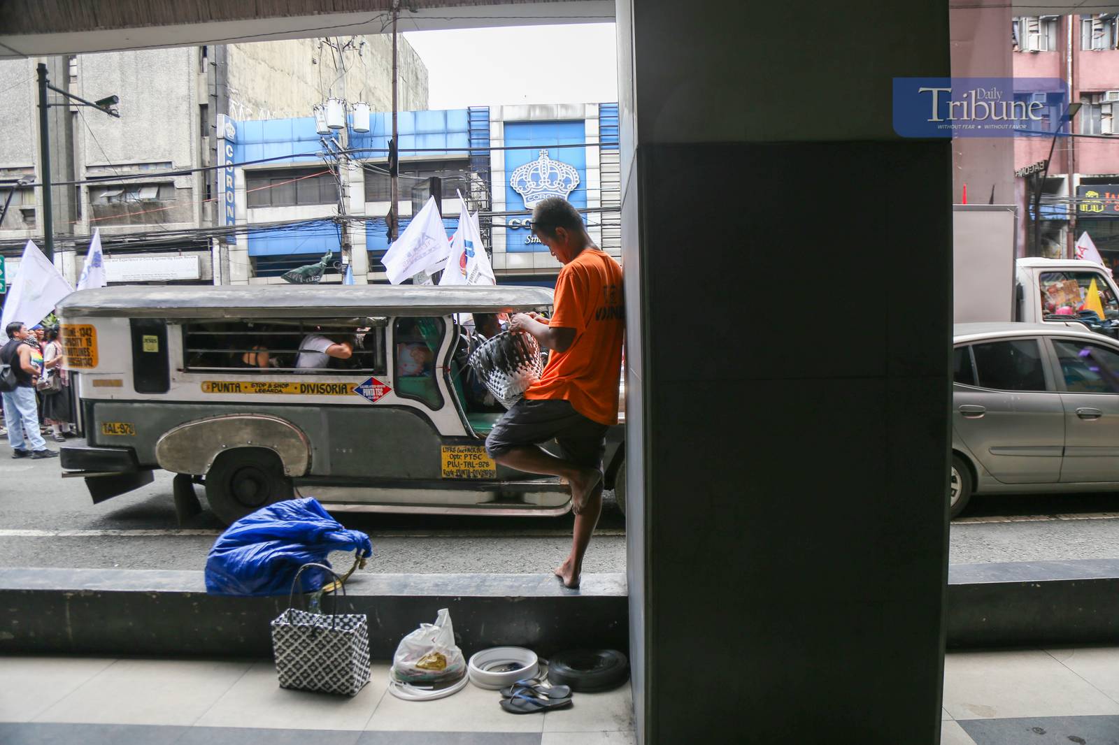 Roy Roja, 56, weaves "bayong" bags from recycled plastic baler straps along Recto Avenue in Manila on 26 June 2025. A native of Bulacan, Roja sells each handmade bayong for ₱250 and can complete up to three bags a day.