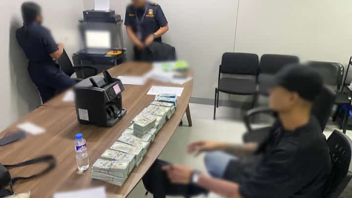 A male passenger (right, wearing a cap) was intercepted by airport authorities after being caught with P1.2 million and USD580,000 in undeclared cash at NAIA Terminal 3.