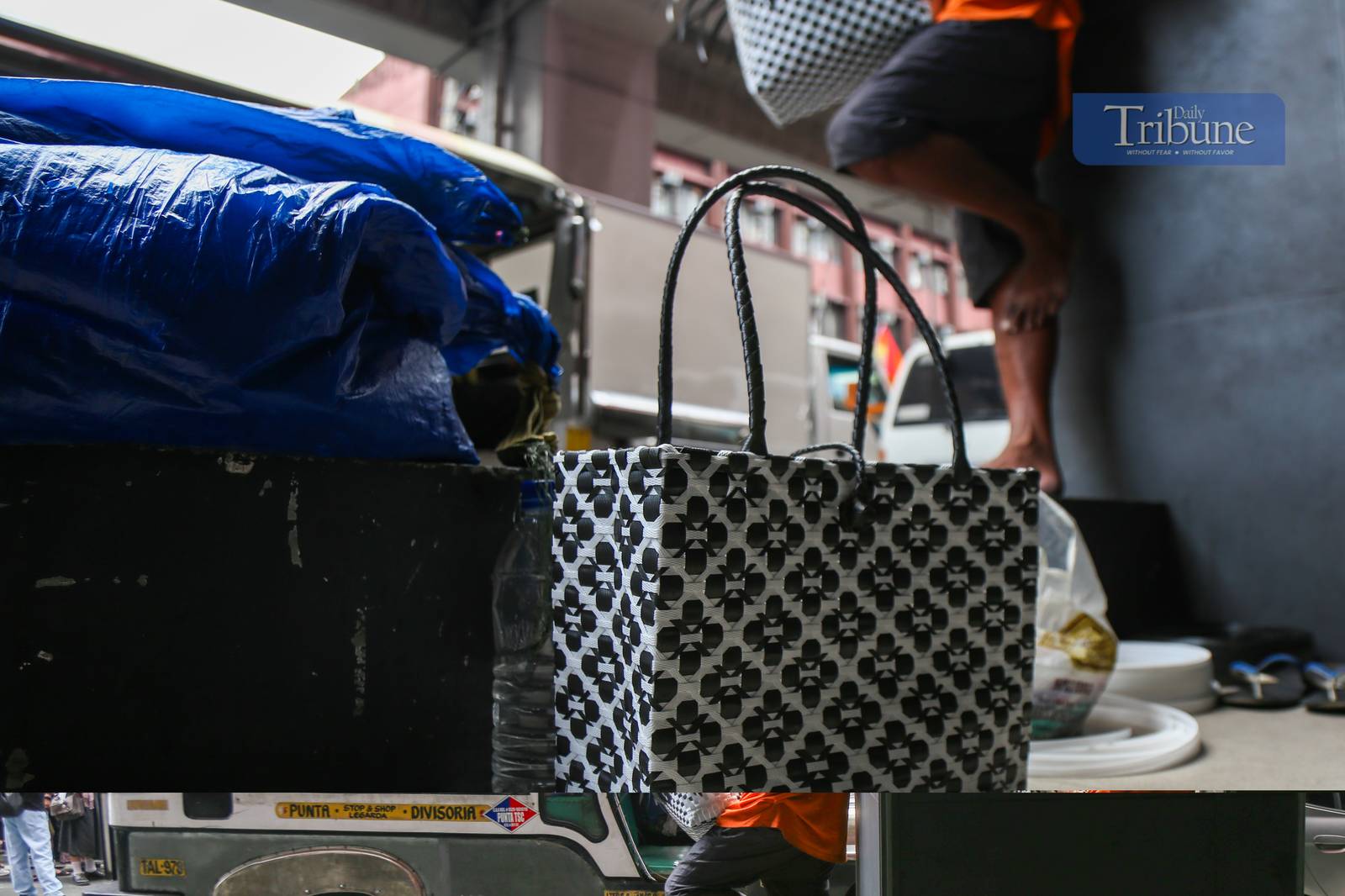 Roy Roja, 56, weaves "bayong" bags from recycled plastic baler straps along Recto Avenue in Manila on 26 June 2025. A native of Bulacan, Roja sells each handmade bayong for ₱250 and can complete up to three bags a day.
