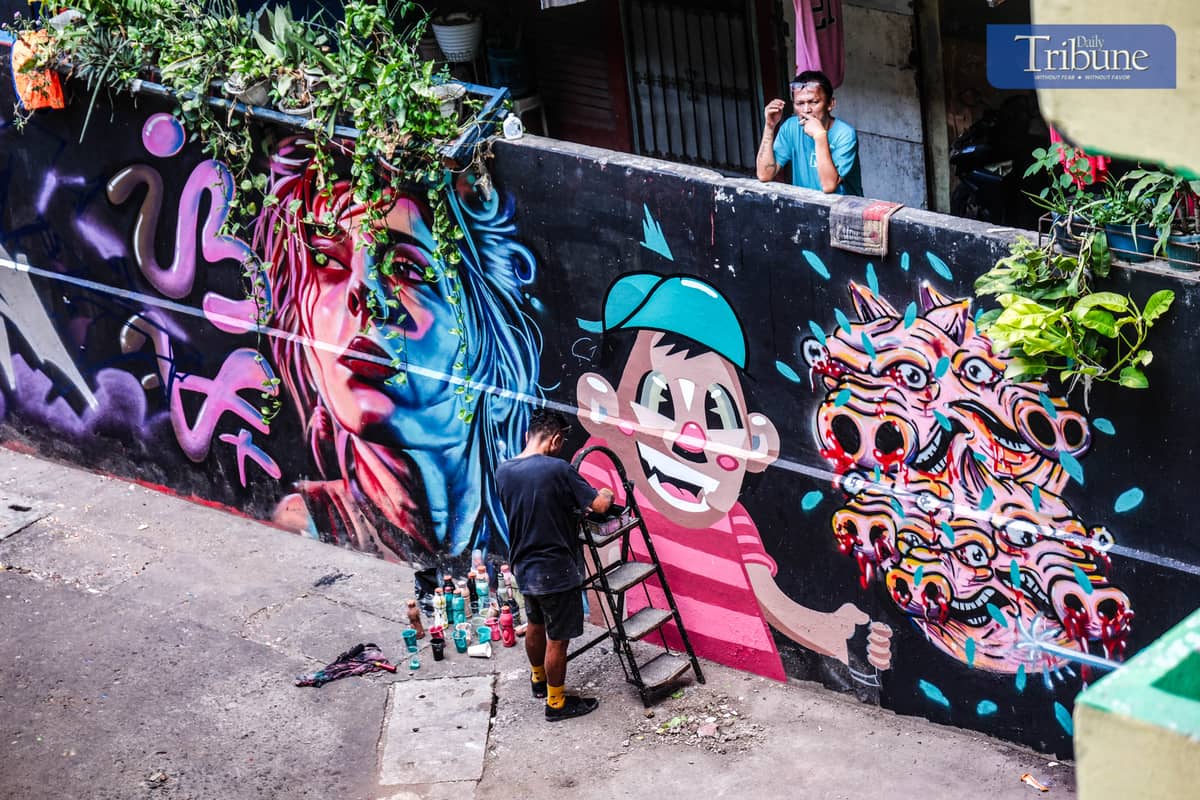 A MAN smokes while watching artists create their grafiti. PHOTO BY YUMMIE DINGDING