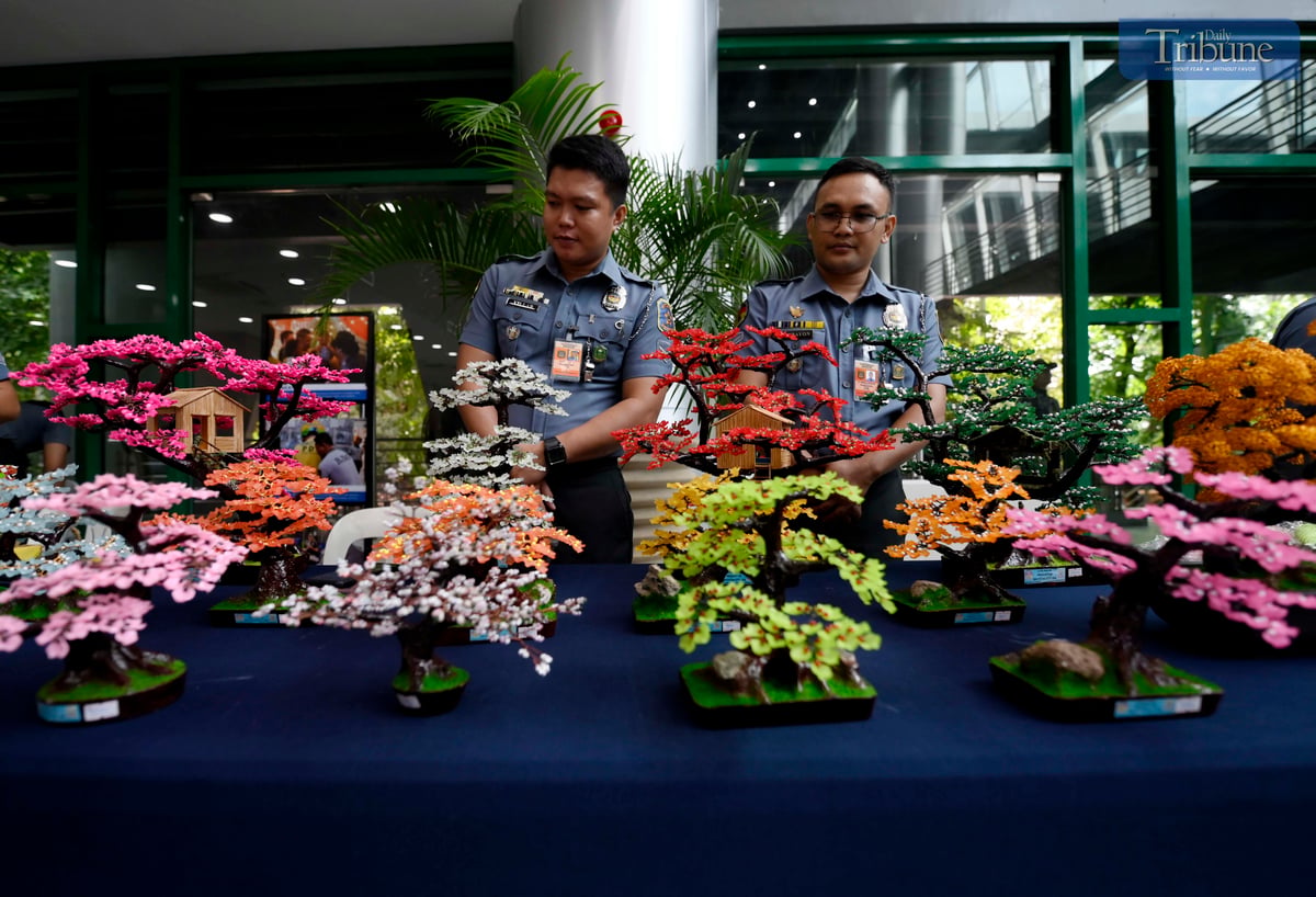 Bureau of Jail Management and Penology (BJMP) personnel arrange handcrafted wire-beaded bonsai trees made by persons deprived of liberty (PDLs) for sale during the agency’s 34th anniversary celebration on Wednesday, July 2, 2025. Proceeds from the decorative pieces support PDL artists and their families.